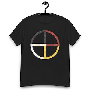 Peut inclure: T-shirt noir avec un motif circulaire divisé en quatre sections. Les sections sont de couleur noire, rouge, blanche et jaune, avec un aspect cousu. Le motif est centré sur le devant du t-shirt.
