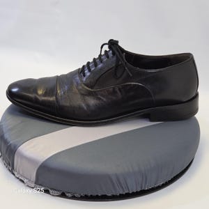 Puede incluir: Un zapato oxford de cuero negro con puntera, que presenta un cierre de cordones con cordones negros finos y un tac&oacute;n bajo apilado. El zapato tiene un acabado liso y pulido y una silueta estructurada con un dise&ntilde;o cl&aacute;sico.