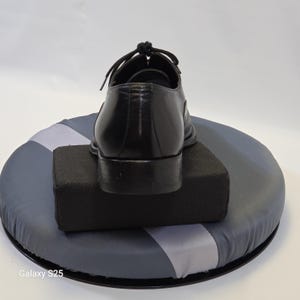 Puede incluir: Un zapato tipo oxford de cuero negro con tac&oacute;n bajo, punta redondeada y cordones negros atados en la parte superior. El zapato se muestra desde la parte posterior, destacando el contrafuerte de cuero liso y los detalles de costura en la parte trasera.