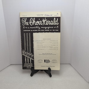 Pode incluir: A revista The Choir Herald de fevereiro de 1955, com tema de Páscoa. A capa é em preto e branco, com o título da revista em uma fonte decorativa. A revista está apoiada em um suporte preto.