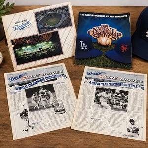 May include: A collection of Los Angeles Dodgers memorabilia including a baseball, a navy blue baseball cap with a white LA logo, a 1988 National League Championship Series program, a commemorative folder, and two Line Drives newsletters featuring team photos.