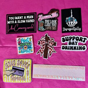 Pode incluir: Cole&ccedil;&atilde;o de patches bordados com v&aacute;rios designs e texto. Inclui patches com frases como "You Want a Man With a Slow Hand", "Excuse Me You Look Like You Love Me" e "Jesus Saves Spend".