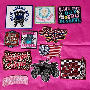 Pode incluir: Cole&ccedil;&atilde;o de patches bordados com v&aacute;rios designs e textos, incluindo "Blue Collar Bitch", "Trophy Wife" e "American Made". Outros patches apresentam um quadriciclo e as palavras "Vintage Soul".