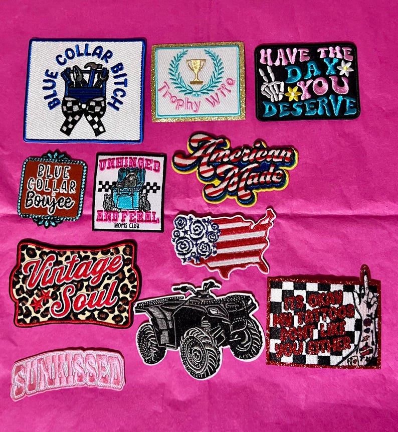 Pode incluir: Cole&ccedil;&atilde;o de patches bordados com v&aacute;rios designs e textos, incluindo "Blue Collar Bitch", "Trophy Wife" e "American Made". Outros patches apresentam um quadriciclo e as palavras "Vintage Soul".