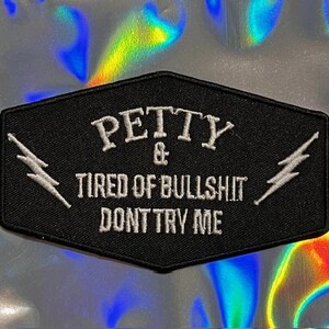 May include: Black embroidered patch with white text that reads "PETTY & TIRED OF BULLSHIT DONT TRY ME". The patch is a hexagon shape with a white lightning bolt on each side.