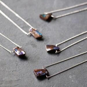 Pode incluir: Cinco colares de prata com pingentes de pedra de opala iridescente. As pedras s&atilde;o todas de formas e tamanhos diferentes, mas todas t&ecirc;m um esquema de cores semelhante, marrom e azul.