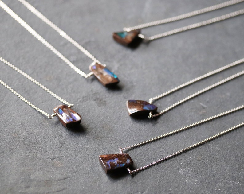 Pode incluir: Cinco colares de prata com pingentes de pedra de opala iridescente. As pedras s&atilde;o todas de formas e tamanhos diferentes, mas todas t&ecirc;m um esquema de cores semelhante, marrom e azul.