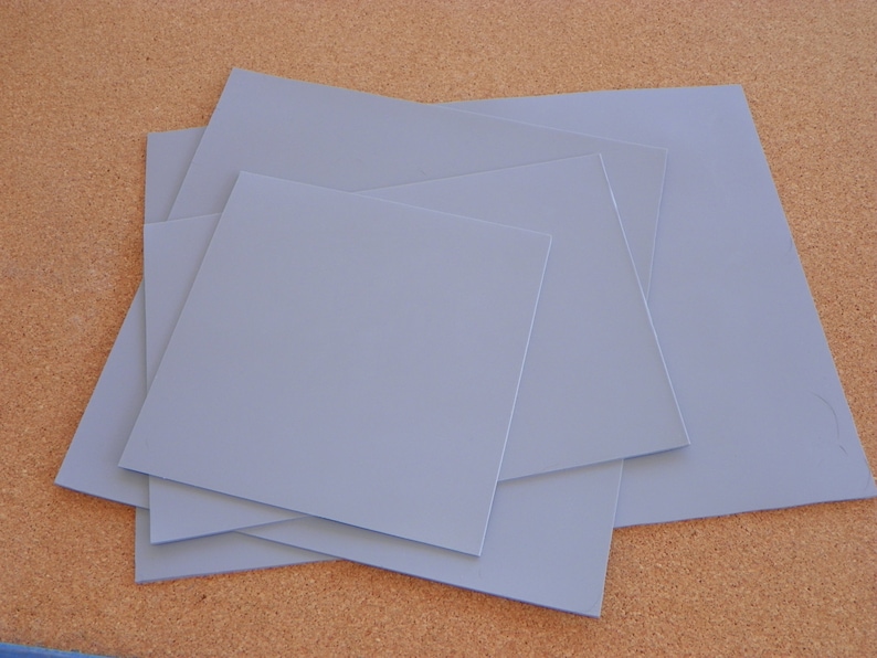 May include: Four sheets of light blue thermal pad material stacked on top of each other.