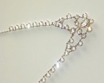 May include: A silver necklace with a teardrop-shaped pendant and a delicate chain adorned with small, clear rhinestones.
