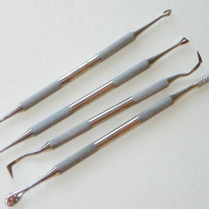 May include: Set of four stainless steel tools with different shaped tips. The tools are used for crafting and sculpting.