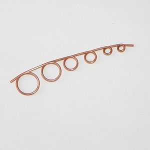 May include: A copper wire with five loops of varying sizes, creating a graduated effect. The wire is bent into a curved shape.