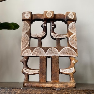 May include: A rectangular brown wooden sculpture featuring an openwork design of four stylized birds. The wood has a dark, weathered finish with white etched details highlighting the bird shapes, circular eyes, and curved wing patterns throughout.