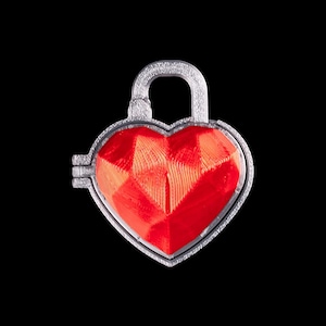 Puede incluir: Un candado plateado en forma de corazón con un centro rojo brillante y facetado. El candado tiene un asa curva y una superficie texturizada detallada. El diseño en forma de corazón destaca sobre un fondo negro.