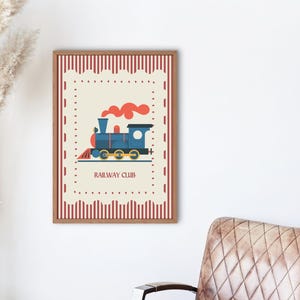 May include: A framed print featuring a blue train illustration with red smoke and the text "RAILWAY CLUB." The artwork has a cream-colored background with a red and white border. The frame is brown.