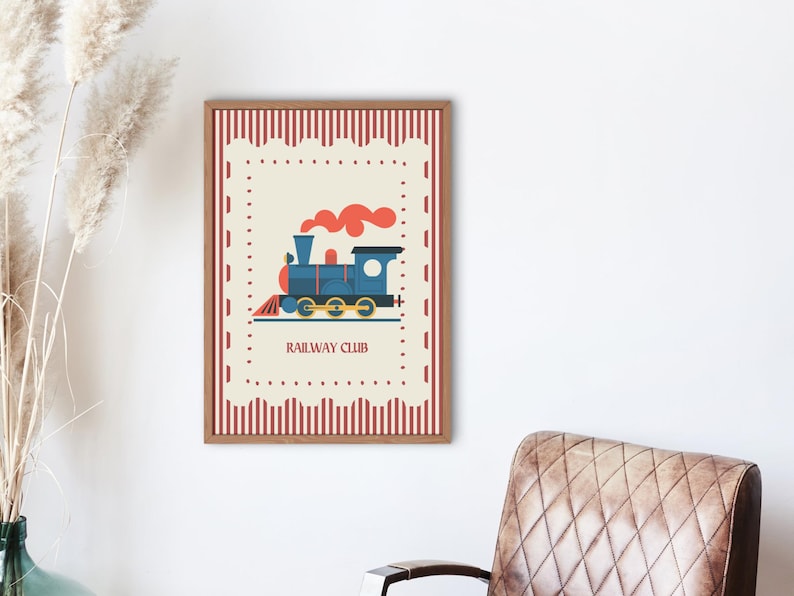 May include: A framed print featuring a blue train illustration with red smoke and the text "RAILWAY CLUB." The artwork has a cream-colored background with a red and white border. The frame is brown.
