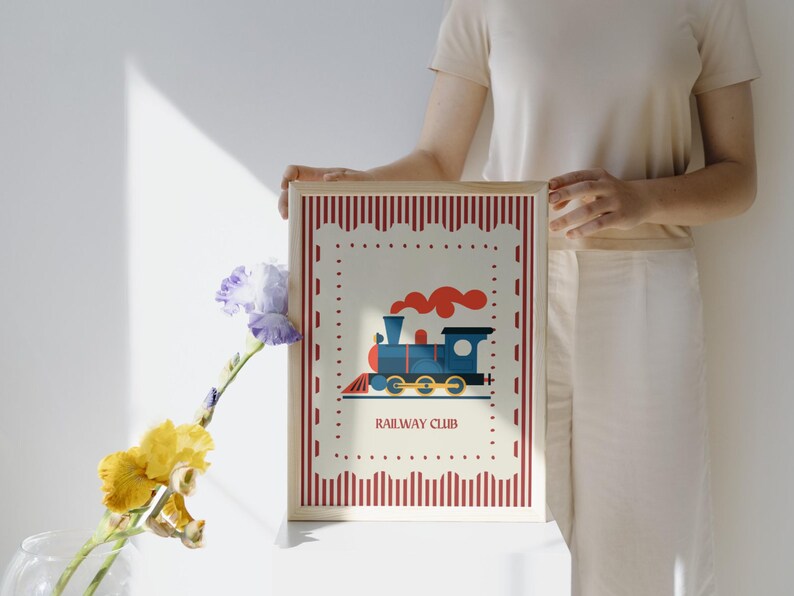 May include: A framed print featuring a blue train with red smoke, set against a cream background with a red striped border. The text "RAILWAY CLUB" is below the train illustration. The frame is light brown.