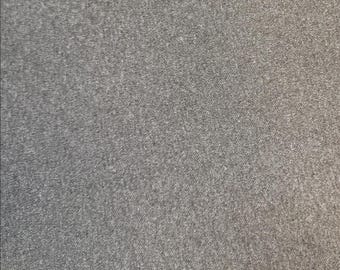 Puede incluir: Primer plano de una tela gris con una superficie texturizada. La tela parece ser un material de peso medio, posiblemente un tejido de punto o tejido. El color es un gris liso y neutro, adecuado para diversos proyectos de ropa o artesanía.