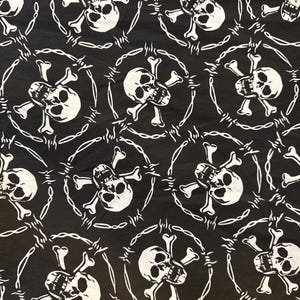Pode incluir: Tecido preto com um padrão repetido de caveiras brancas e ossos cruzados rodeados por arame farpado. O design é um gráfico arrojado e de alto contraste, adequado para roupas ou acessórios com estética punk ou gótica.