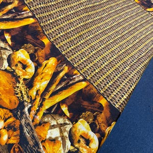 May include: A fabric with a bread-themed pattern, featuring various baked goods in shades of brown and yellow. The design includes baguettes, rolls, and loaves of bread. A separate section has a brown and gold checkered pattern.