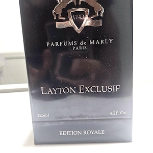 May include: Black rectangular box of Layton Exclusif perfume. The box features a silver emblem of two rearing horses above the text "PARFUMS de MARLY PARIS". The box also has the text "LAYTON EXCLUSIF", "125ml", and "4.2 fl.oz."