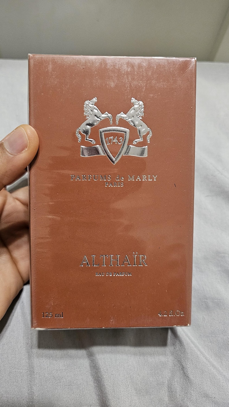 May include: A brown perfume box with the text "ALTHA&Iuml;R Eau de Parfum" and "PARFUMS de MARLY PARIS". The box has a silver emblem with two horses and the number "1743". The box contains 125 ml (4.2 fl oz).