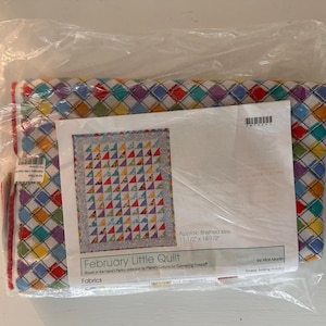 May include: A quilt kit in a clear plastic bag. The quilt has a colorful diamond pattern. The kit includes fabric and a pattern for a quilt that measures approximately 11.5 x 14.5 inches. The pattern is titled "February Little Quilt."