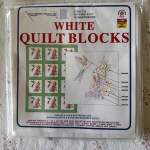 May include: A packaged white quilt block set featuring hummingbird embroidery patterns. The package includes six 18-inch blocks, with instructions for creating a hand-embroidered quilt. The package text reads "White Quilt Blocks" and "Hummingbirds."