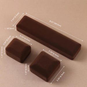 May include: Three brown velvet jewelry boxes of varying shapes and sizes. One long rectangular box measures 8.07 inches by 2.04 inches by 1.18 inches. Two square boxes measure 2.44 inches by 2.04 inches by 1.37 inches and 2.55 inches by 2.55 inches by 1.37 inches.
