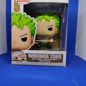 May include: A Funko Pop! Animation figure of Roronoa Zoro from One Piece. The figure has green hair, a white shirt, and is holding a sword. The box is white with the Funko Pop! logo and the number 1775.