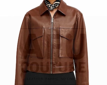 May include: A brown leather jacket with a zip-up front, two front pockets, and a collared neckline. The jacket has a boxy fit and is worn over a black top. The text "COUTURE" and "LEATHER, FABRIC, NO LIMITS" are visible.