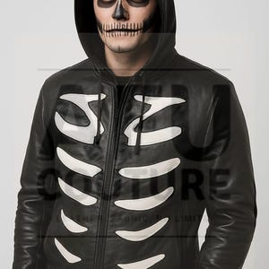 Könnte beinhalten: Schwarze Lederjacke mit Kapuze und weißem Skelettmuster. Die Jacke hat einen durchgehenden Reißverschluss und eine Kapuze. Die Person auf dem Bild hat ein Totenkopf-Make-up. Die Jacke ist ein Halloween-Kostüm.
