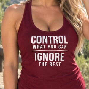May include: A maroon racerback tank top featuring white text that reads CONTROL WHAT YOU CAN IGNORE THE REST. The garment has a scoop neckline and a sleeveless design, with the text printed in a bold, sans-serif font across the chest area.