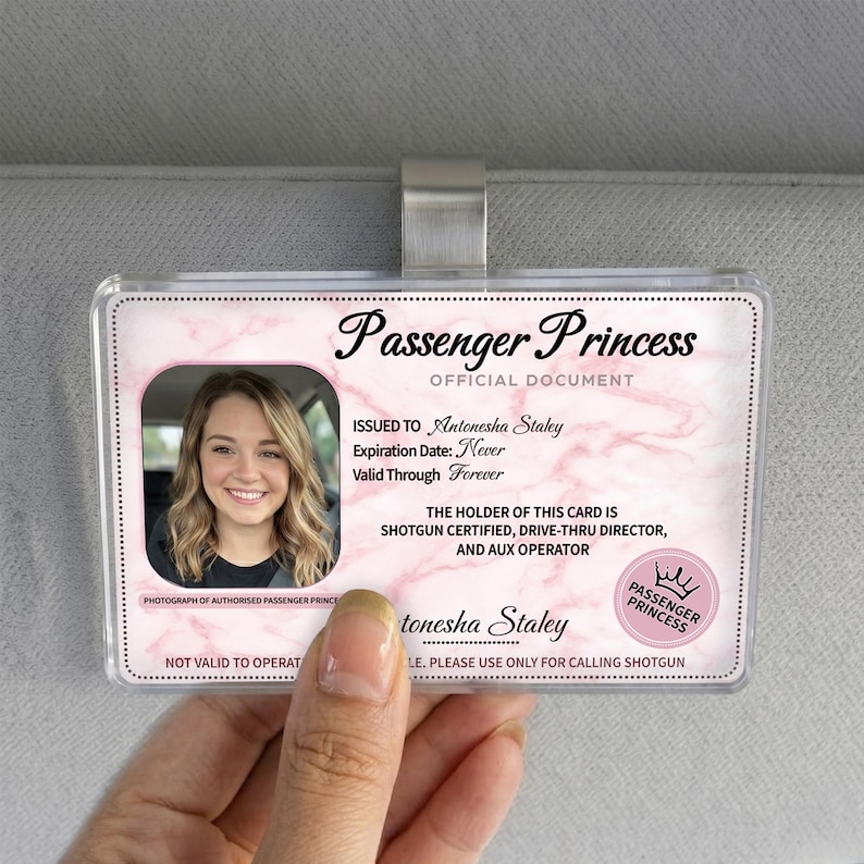 Puede incluir: Documento oficial de &laquo;&nbsp;Passenger Princess&nbsp;&raquo; de pl&aacute;stico transparente, con foto de una mujer sonriente. El fondo es rosa marmolado y el texto indica &laquo;&nbsp;Shotgun Certified, Drive-Thru Director, and Aux Operator&nbsp;&raquo;.