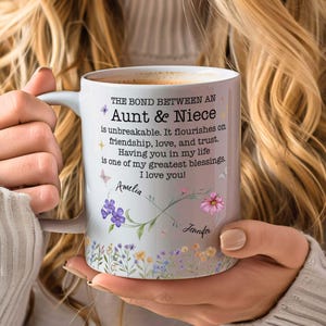 May include: A white ceramic mug featuring the text The bond between an Aunt & Niece is unbreakable. It flourishes on friendship, love, and trust. Having you in my life is one of my greatest blessings. I love you! with floral and butterfly graphics.