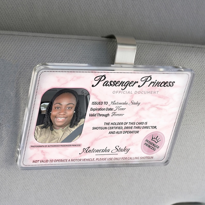 Puede incluir: Una tarjeta de visera de coche Passenger Princess de pl&aacute;stico transparente con una foto de una mujer sonriente. La tarjeta tiene un dise&ntilde;o de m&aacute;rmol rosa y el texto "Passenger Princess Official Document". Incluye el nombre "Antonesha Staley".