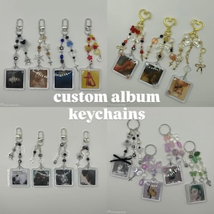 Puede incluir: Una colección de llaveros de álbumes personalizados. Cada llavero presenta una pequeña imagen cuadrada de la portada del álbum en plástico transparente. Los llaveros están adornados con cuentas, abalorios y detalles metálicos. El texto "custom album keychains" está presente.