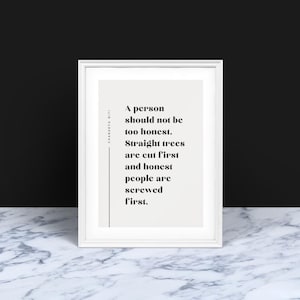 Op de afbeelding: Een ingelijste print met een witte rand, met zwarte tekst op een lichtbeige achtergrond. De quote luidt: "Een persoon moet niet te eerlijk zijn. Rechte bomen worden eerst geveld en eerlijke mensen worden eerst genaaid."