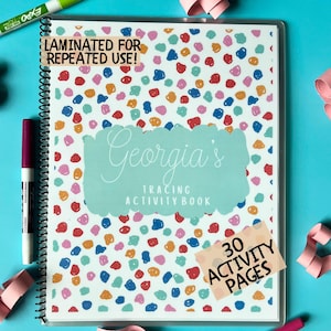 May include: A spiral-bound tracing activity book with a colorful polka dot pattern. The cover features the text "Georgia's TRACING ACTIVITY BOOK" and "LAMINATED FOR REPEATED USE!" with a sticker that says "30 ACTIVITY PAGES". A green and a purple marker are visible.