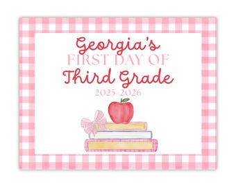 May include: A rectangular sign with a pink gingham border and a white interior. The text "Georgia's FIRST DAY OF THIRD GRADE 2025-2026" is written in red and pink script. A stack of books, a red apple, and a pink bow are also featured.
