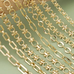 Puede incluir: Primer plano de varios collares de cadena dorados con diversos diseños de eslabones. Las cadenas están dispuestas en diagonal sobre un fondo verde claro, mostrando diferentes estilos, incluyendo eslabones ovalados, rectangulares y decorativos. Las cadenas son brillantes y reflejan la luz.