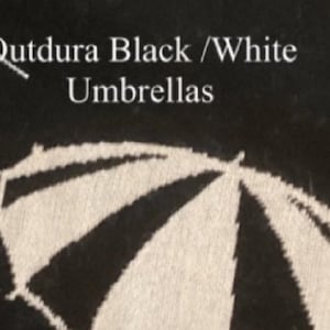 May include: A black and white graphic print featuring a stylized umbrella design. The text Qutdura Black /White Umbrellas is printed in white lettering above the umbrella illustration, which displays alternating black and white panels.