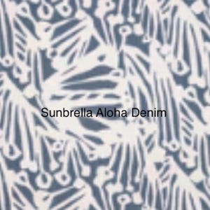 May include: A fabric swatch featuring a repeating white abstract botanical pattern on a denim blue background. The text Sunbrella Aloha Denim is printed in the center of the image in a clear, black, sans-serif font against the patterned fabric.