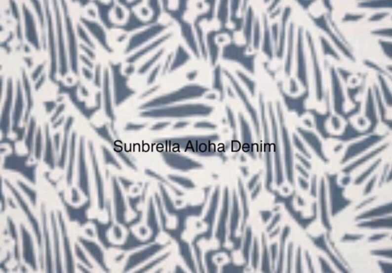 May include: A fabric swatch featuring a repeating white abstract botanical pattern on a denim blue background. The text Sunbrella Aloha Denim is printed in the center of the image in a clear, black, sans-serif font against the patterned fabric.
