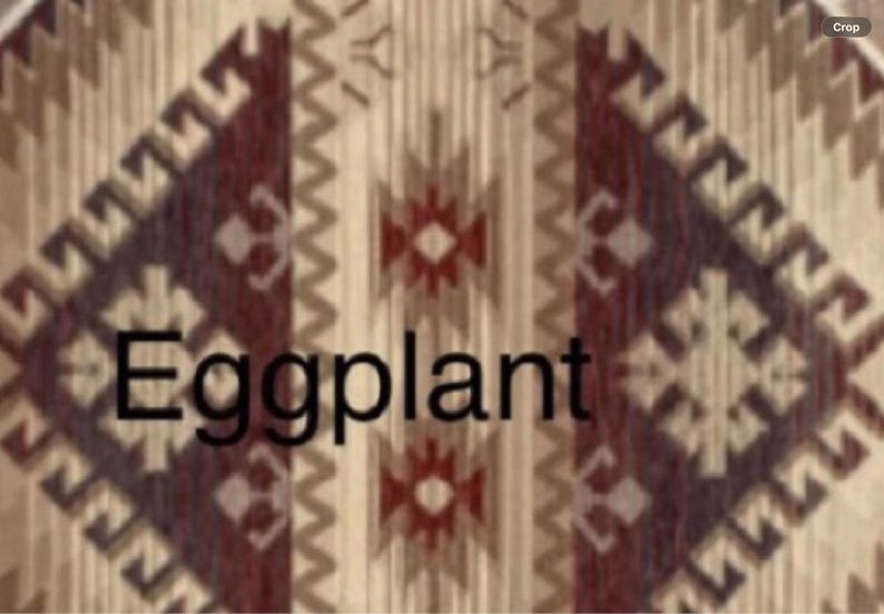May include: A textile featuring a repeating geometric pattern in shades of beige, cream, and deep eggplant purple. The design includes zigzag lines and diamond shapes arranged in vertical columns. The word Eggplant is printed in black text.