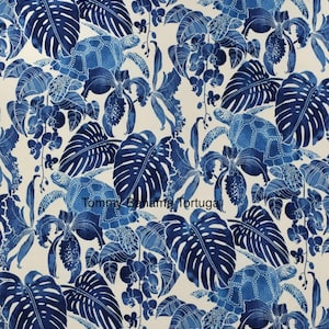 Peut inclure: Un tissu avec un motif r&eacute;p&eacute;titif de tortues de mer bleues, de feuilles tropicales et d'orchid&eacute;es sur un fond cr&egrave;me. Le texte "Tommy Bahama Tortuga" est visible. Le motif est de style aquarelle avec diff&eacute;rentes nuances de bleu.
