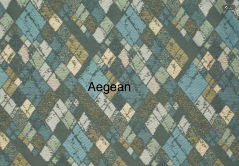 May include: A fabric swatch featuring a repeating diamond argyle pattern in shades of dark green, teal, light blue, and cream. The design has a distressed, textured appearance throughout the shapes. The word Aegean is printed in black in the center.