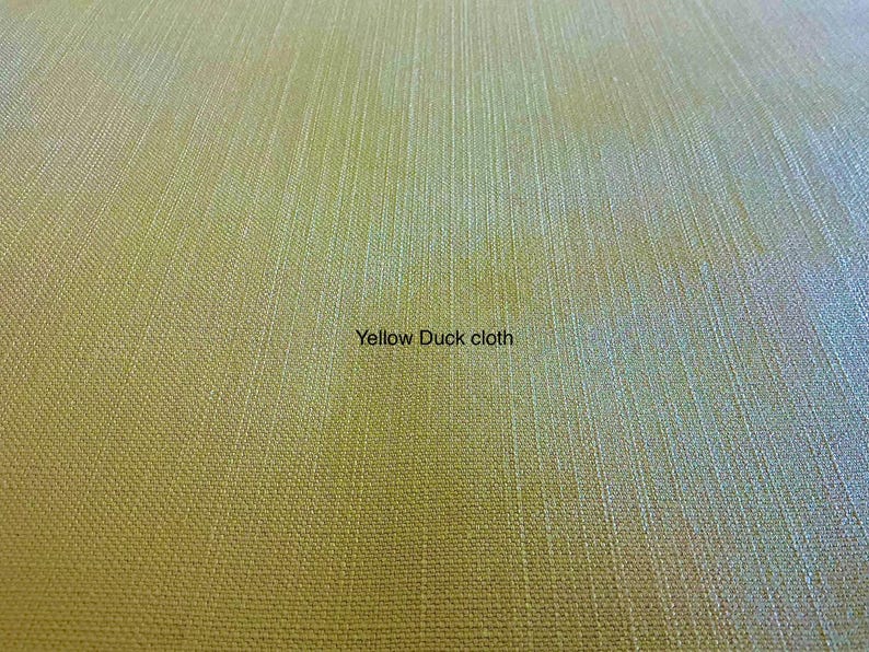 May include: A close-up view of yellow duck cloth fabric featuring a distinct, tightly woven texture with visible vertical and horizontal threads. The surface displays a uniform, matte yellow color throughout, with the text Yellow Duck cloth.