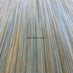 May include: A fabric textile featuring a vertical striped pattern in shades of blue, yellow, and white. The material has a woven, textured appearance with fine lines running parallel across the surface. The text Blue/Yellow stripe is visible.