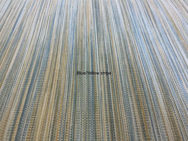 May include: A fabric textile featuring a vertical striped pattern in shades of blue, yellow, and white. The material has a woven, textured appearance with fine lines running parallel across the surface. The text Blue/Yellow stripe is visible.