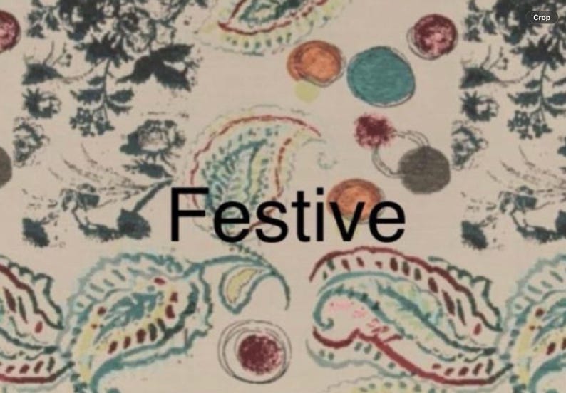 May include: A cream-colored fabric featuring a repeating pattern of dark blue floral motifs, teal and red paisley shapes, and scattered multicolored circles. The word Festive is printed in bold black sans-serif letters across the center.